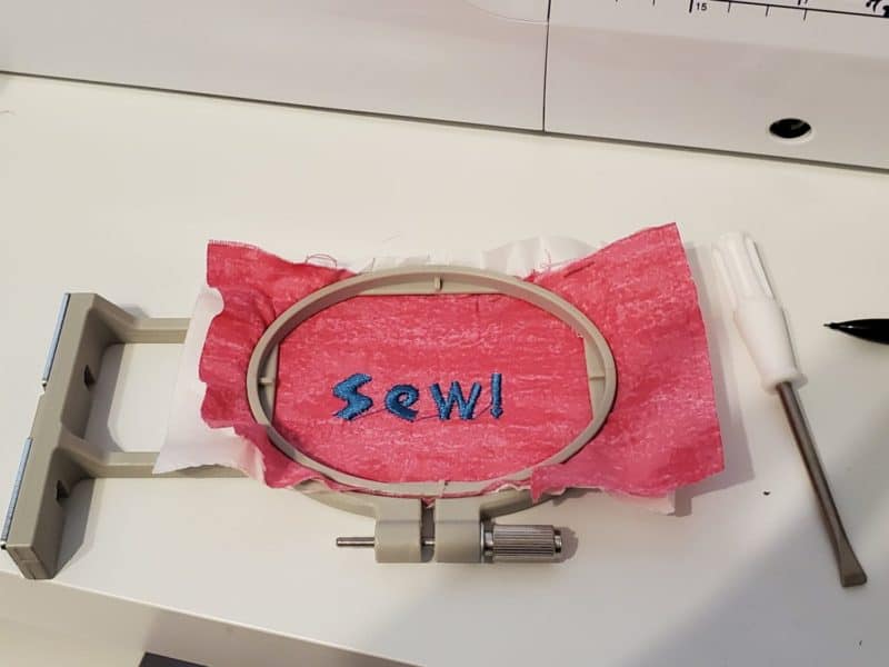 embroidering "Sew!" on a piece of fabric