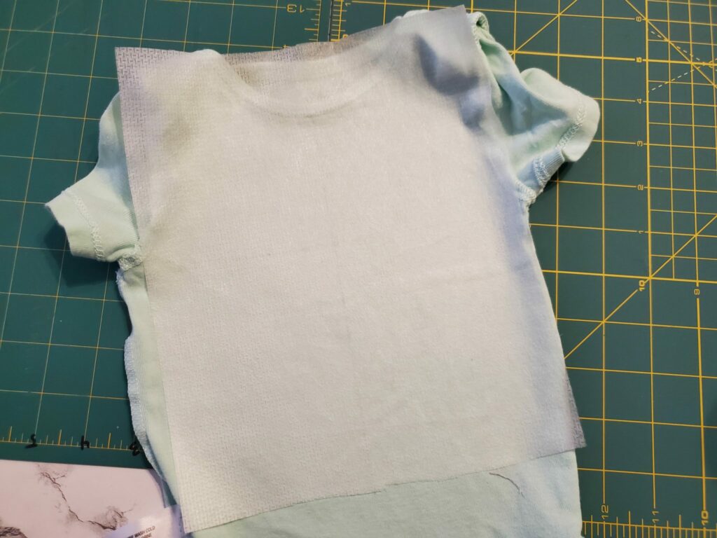 adhere cut-away or no show mesh stabilizer to the back of the onesie